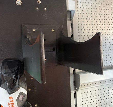 Wzmocniony pomarańczowy uchwyt ścienny z druku 3D do profesjonalnej kosy spalinowej STIHL FS 460 zamontowany na ścianie.