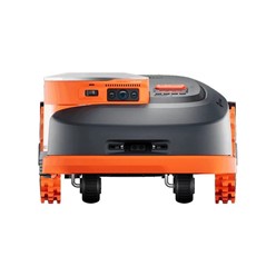 Robot Segway Navimow H206 z włączonym oświetleniem LED kosi trawę nocą przy krawędzi ogrodzenia.