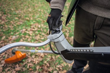 Kosa akumulatorowa STIHL FSA 200 z ergonomicznym oburęcznym uchwytem, widok z przodu na cały produkt, biało-pomarańczowa obudowa