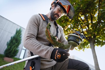 Elektryczna kosza marki Stihl z widocznym silnikiem i głowicą tnącą.