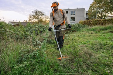 Kosa akumulatorowa STIHL FSA 200 z ergonomicznym oburęcznym uchwytem, widok z przodu na cały produkt, biało-pomarańczowa obudowa