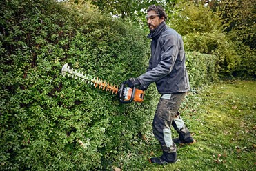 Akumulatorowe nożyce do żywopłotu STIHL HSA 100. Urządzenie ma charakterystyczną biało-pomarańczową kolorystykę.